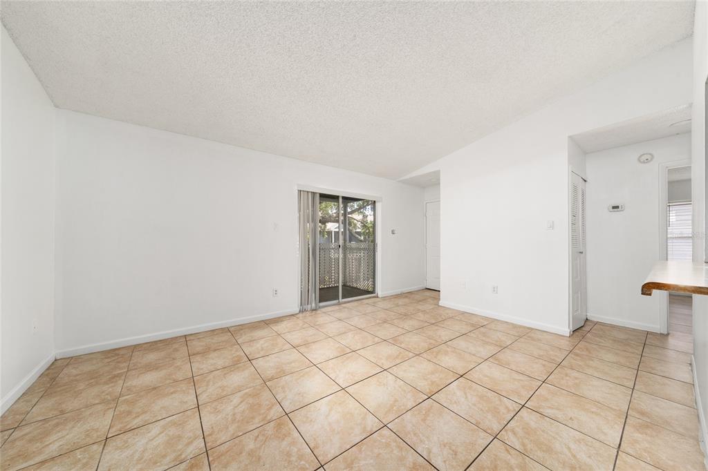 An empty room with beige tile flooring, white walls, and a sliding glass door — 3849 BAY CLUB CIRCLE UNIT 204, KISSIMMEE, FL