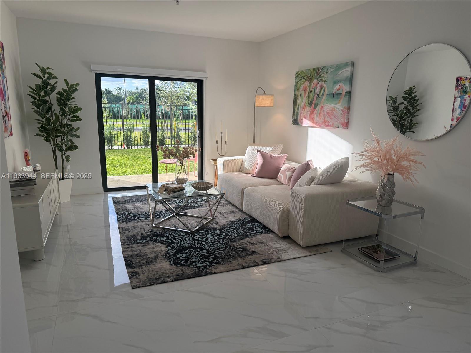 A bright living room features a white sofa, glass coffee table, and sliding glass patio doors — 2306 E 4th ave # 303, Hialeah FL 33013, HIALEAH, FL