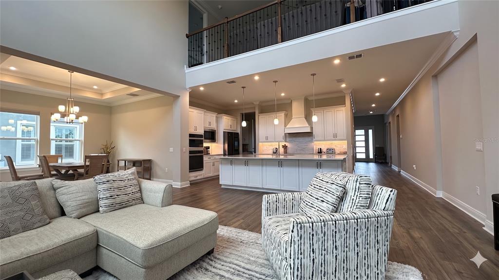 A spacious open-concept living area features a kitchen with white cabinetry and a large island — 6875 BROGLIE STREET, ORLANDO, FL