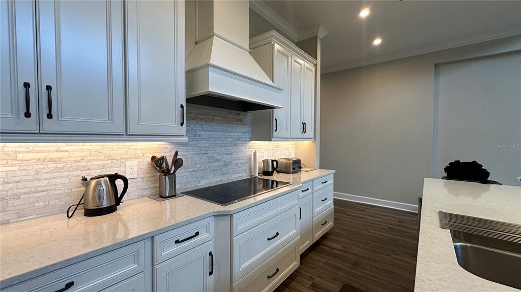 A kitchen features light gray cabinets, white countertops, a tiled backsplash, and stainless steel appliances — 6875 BROGLIE STREET, ORLANDO, FL