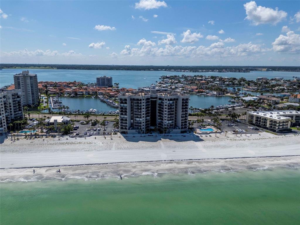 An aerial view shows high-rise condominiums situated directly on a sandy beach along the coast — 1660 GULF BOULEVARD UNIT 407, CLEARWATER BEACH, FL