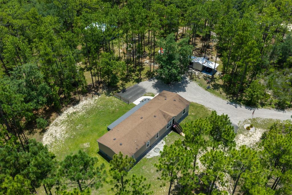 An aerial view shows a single-story house surrounded by trees with a detached garage nearby — 105 BUCK RUN TRAIL, HAWTHORNE, FL