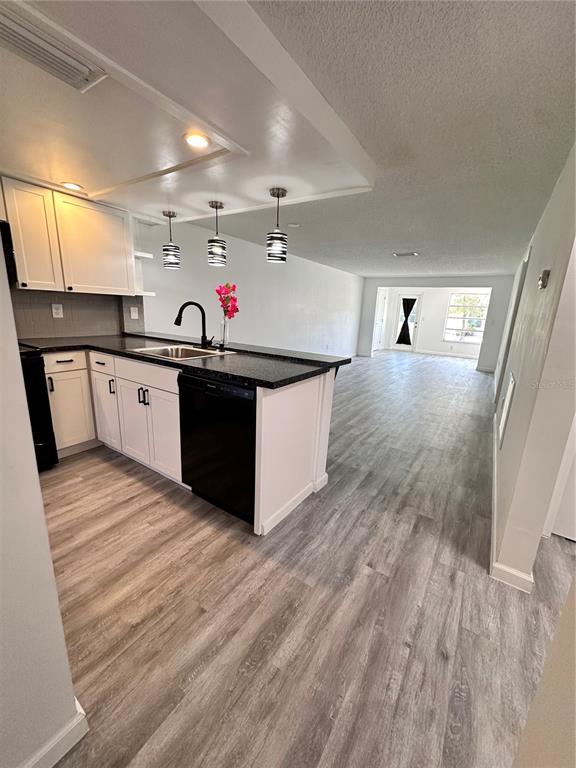A kitchen with white cabinets and a black dishwasher overlooks an open living area — 4445 RUSTIC DRIVE, NEW PORT RICHEY, FL