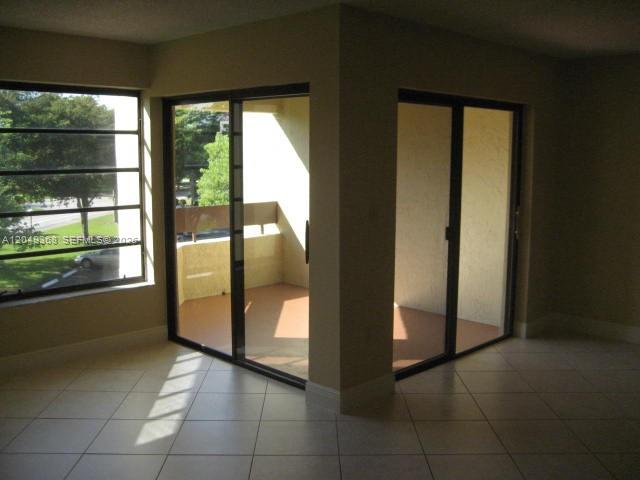An interior room features light-colored tile flooring and sliding glass doors leading to a balcony — 9022 SW 123rd Ct # O303, Miami FL 33186, MIAMI, FL