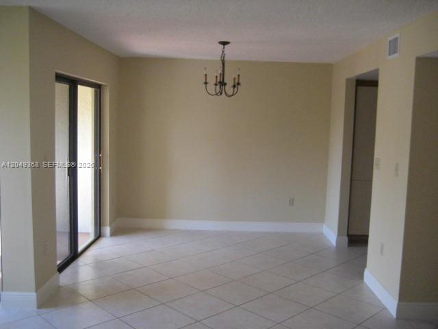 A dining area with beige walls, tile flooring, a chandelier, and a sliding glass door — 9022 SW 123rd Ct # O303, Miami FL 33186, MIAMI, FL
