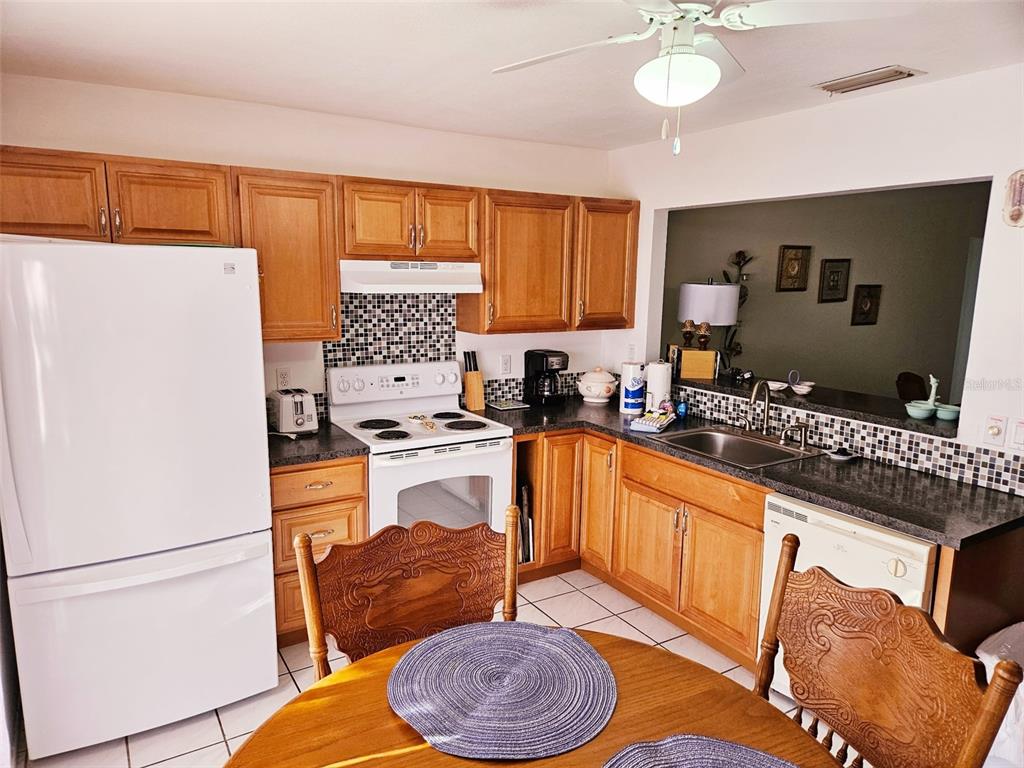 A kitchen features wooden cabinets, a white refrigerator, a stove, and a dining table — 4107 41ST STREET W, BRADENTON, FL