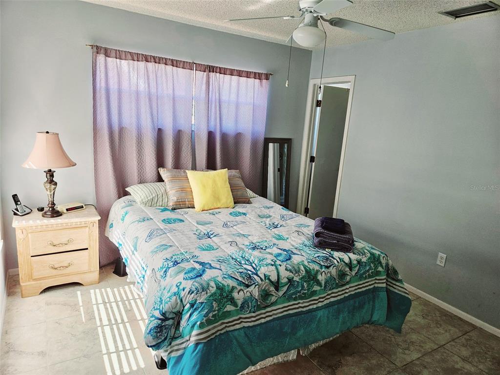 A bedroom features a bed with a coastal-themed comforter, a nightstand, and light blue walls — 4107 41ST STREET W, BRADENTON, FL
