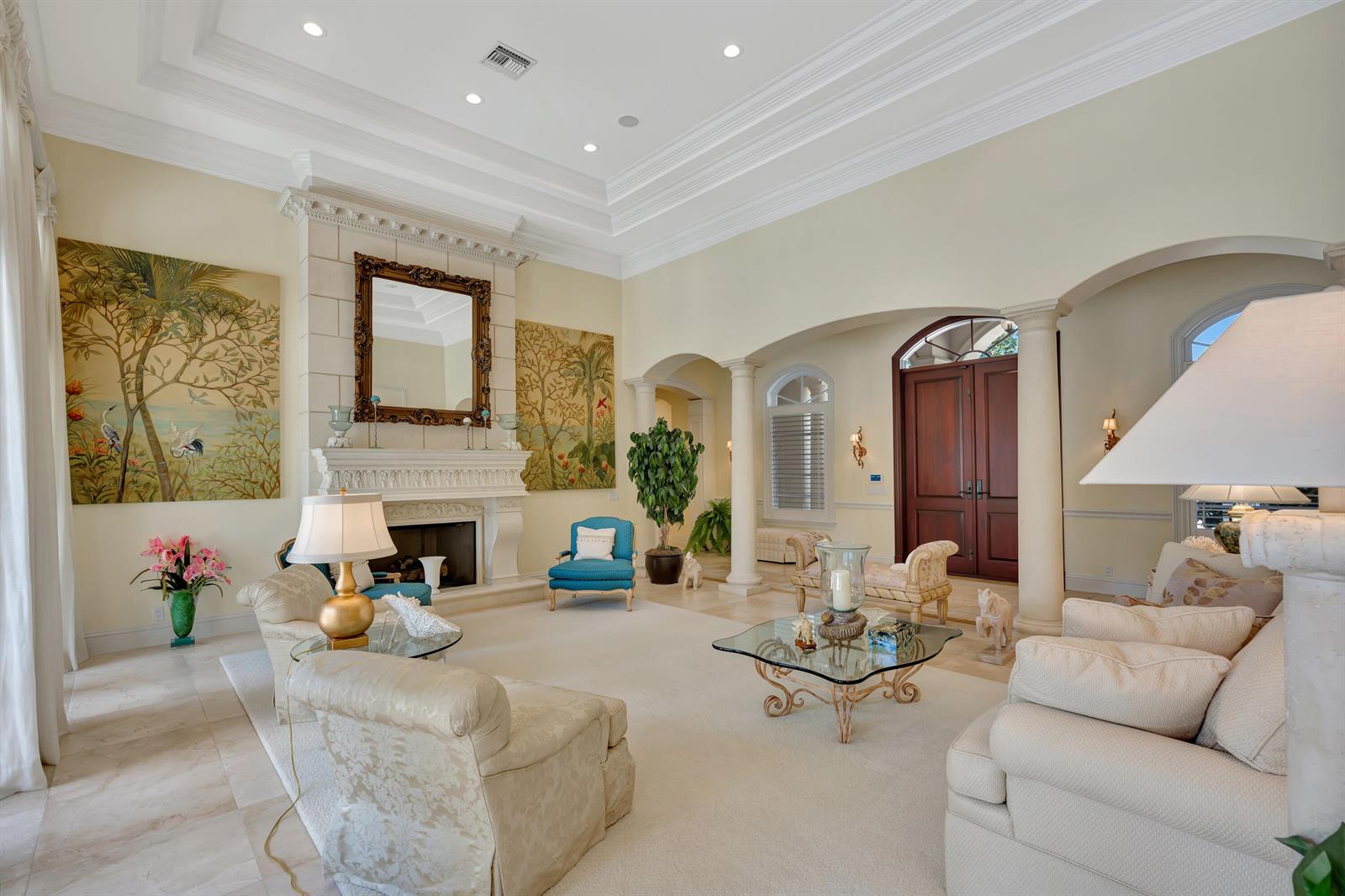 A spacious living room features a fireplace, arched entryways, columns, and neutral-toned furniture — 469 Mariner Drive, Jupiter FL 33477, JUPITER, FL
