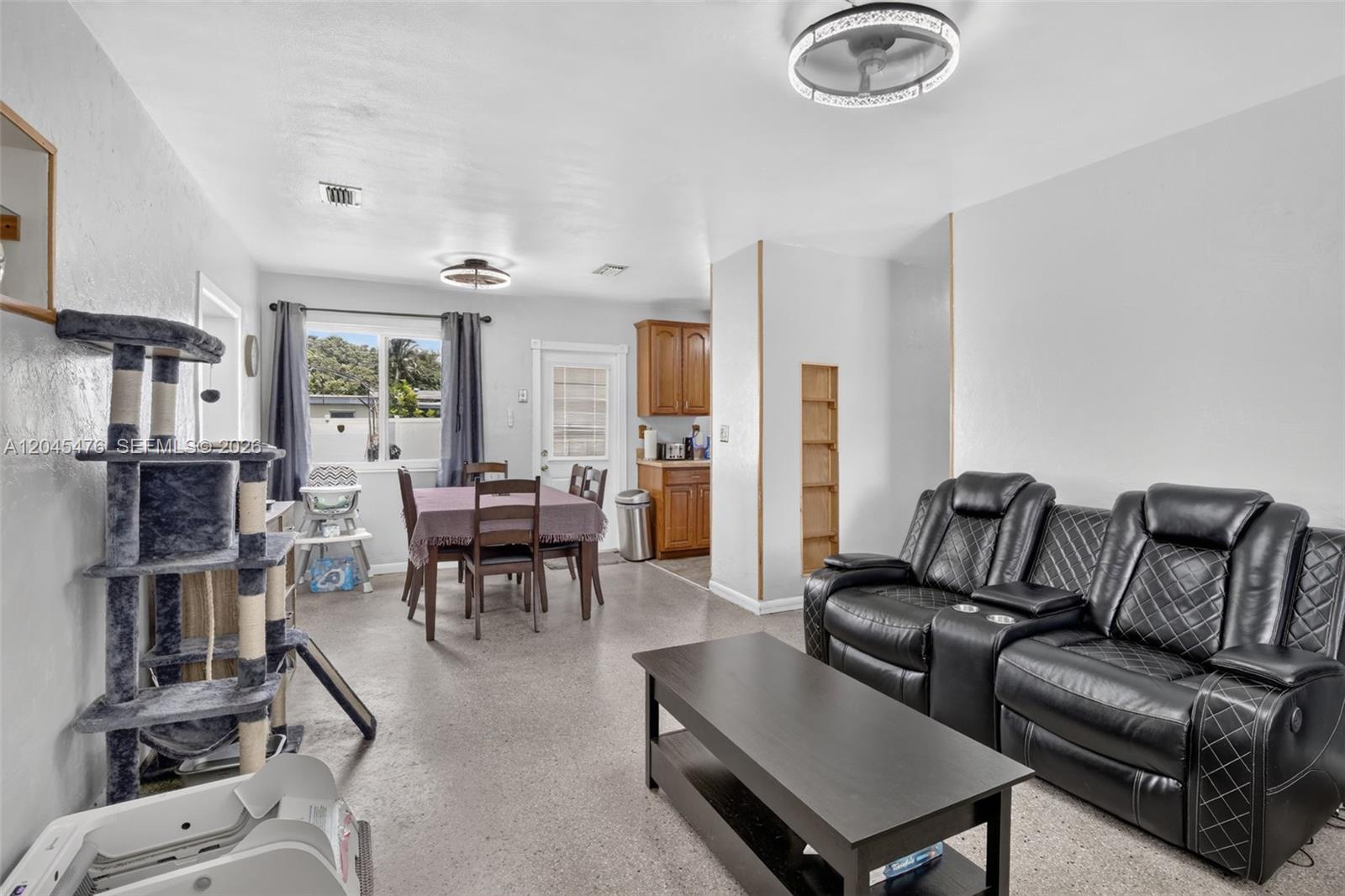 A living and dining area features a black leather sofa, dining table, and cat tree — 7331 Garfield St, Hollywood FL 33024, HOLLYWOOD, FL
