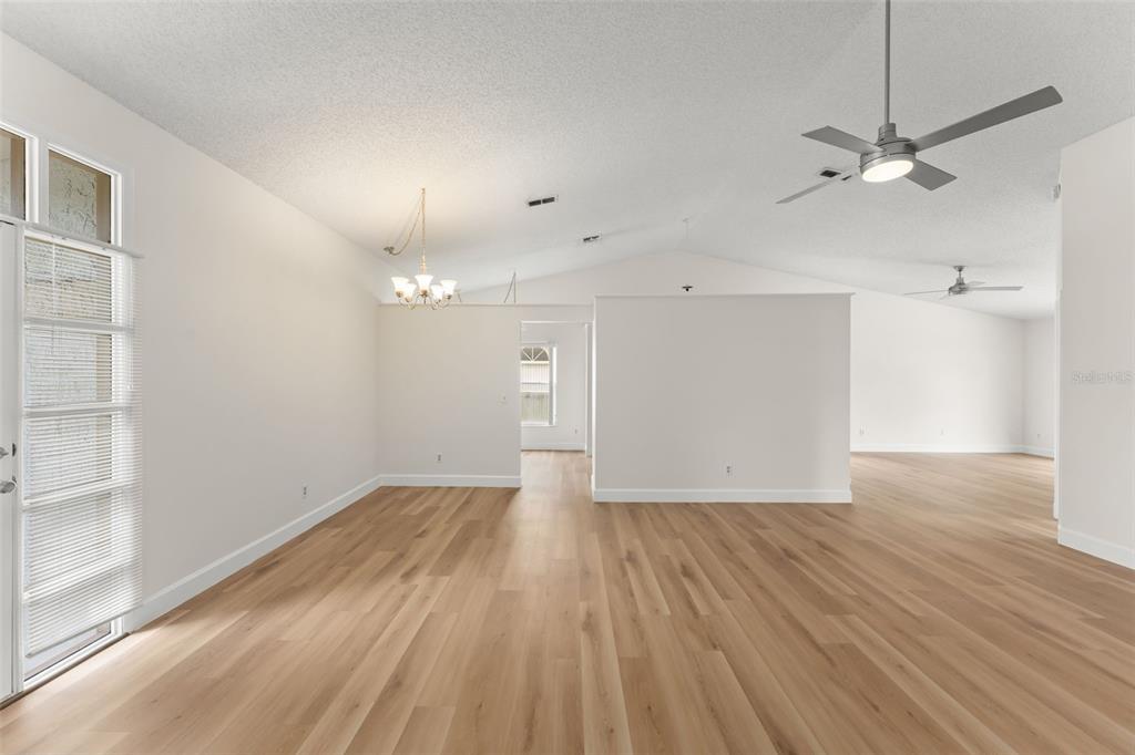 An open-concept living area features light wood-look flooring, a vaulted ceiling, and two ceiling fans — 796 MINERVA LANE, LAKE MARY, FL
