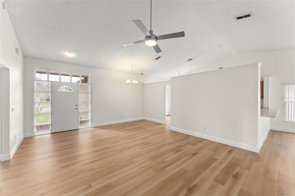 An empty living room features light wood-look flooring, white walls, and a ceiling fan — 796 MINERVA LANE, LAKE MARY, FL