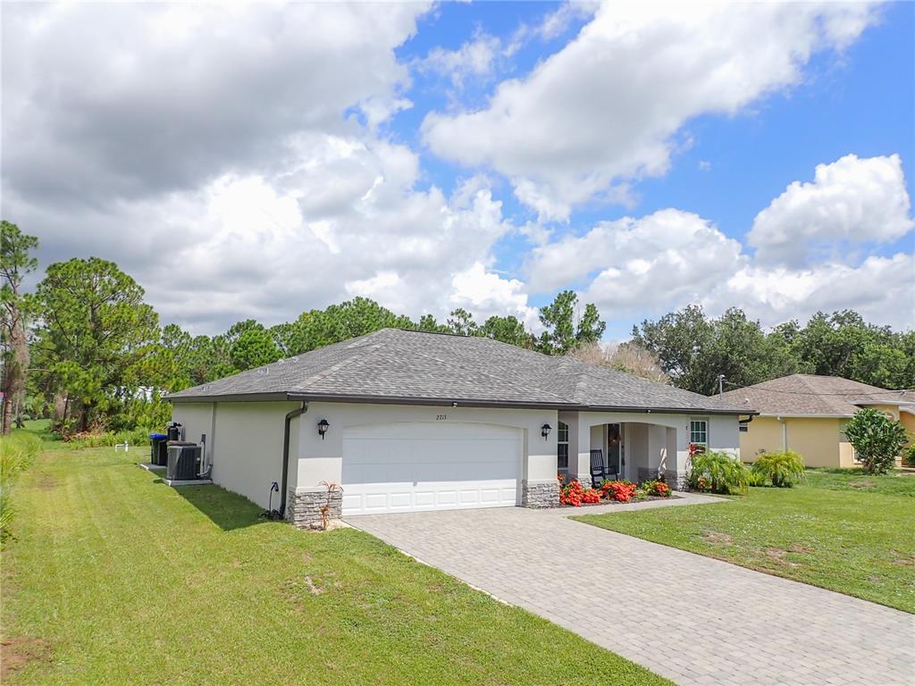 A single-story house with a white garage, stone accents, and a paved driveway — 2713 EMBASSY ROAD, NORTH PORT, FL