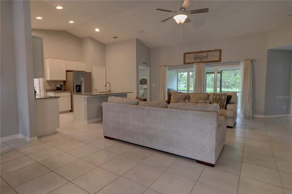 An open-concept living room features light tile flooring, a large sofa, and a kitchen area — 2713 EMBASSY ROAD, NORTH PORT, FL