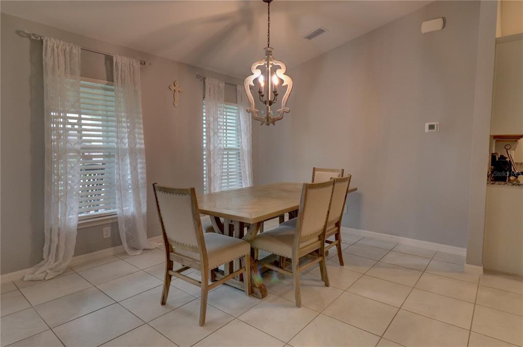 A dining room features a wooden table, four upholstered chairs, and a decorative chandelier — 2713 EMBASSY ROAD, NORTH PORT, FL