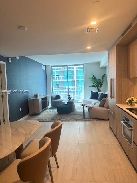 A modern kitchen features light wood cabinetry, marble-style backsplash, and a small dining nook — 77 SE 5th St # 2708, Miami FL 33131, MIAMI, FL