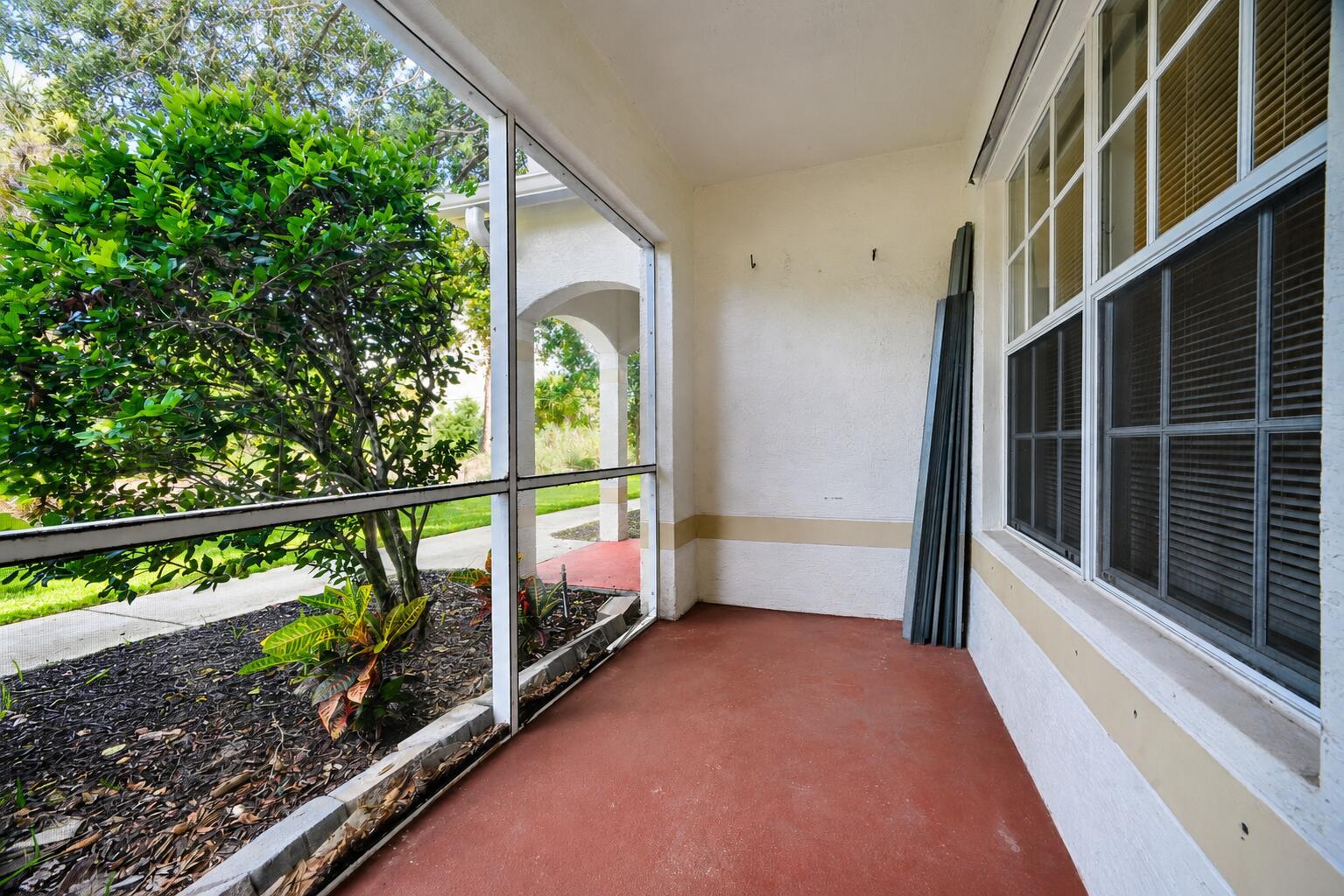 A screened-in porch with a red concrete floor, white walls, and a view of landscaping — 356 SE Rogers Court, Stuart FL 34994, STUART, FL