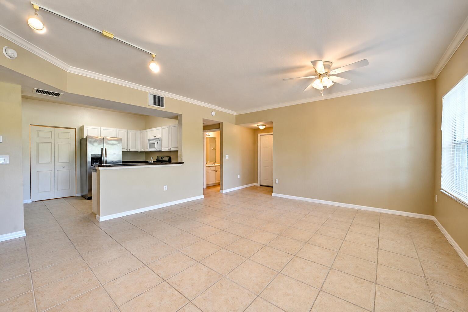 An open-concept living area features beige tile flooring, a kitchen with white cabinets, and a ceiling fan — 356 SE Rogers Court, Stuart FL 34994, STUART, FL