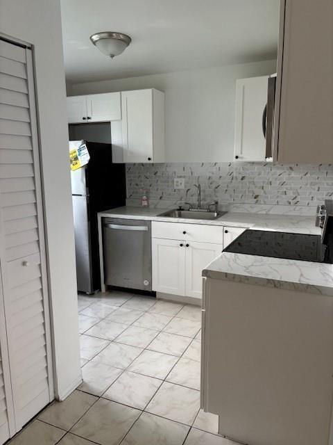 A kitchen features white cabinets, stainless steel appliances, marble-patterned countertops, and a tiled backsplash — 501 Gardens Drive # 101, Pompano Beach FL 33069, POMPANO BEACH, FL