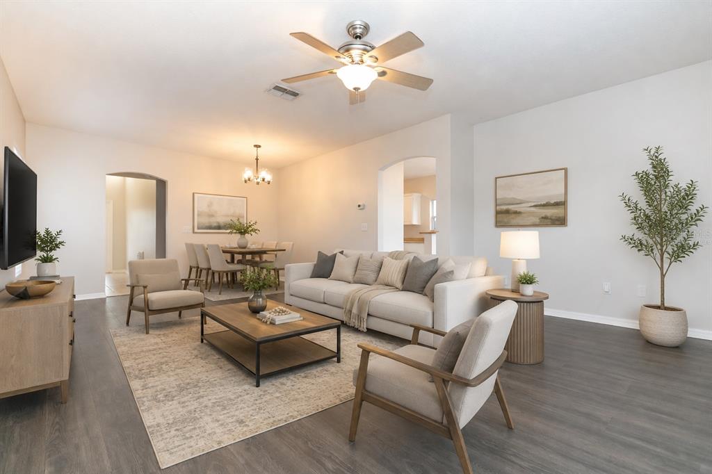A living room with a sofa, two armchairs, a coffee table, and an adjacent dining area — 28632 SEASHELL COURT, WESLEY CHAPEL, FL