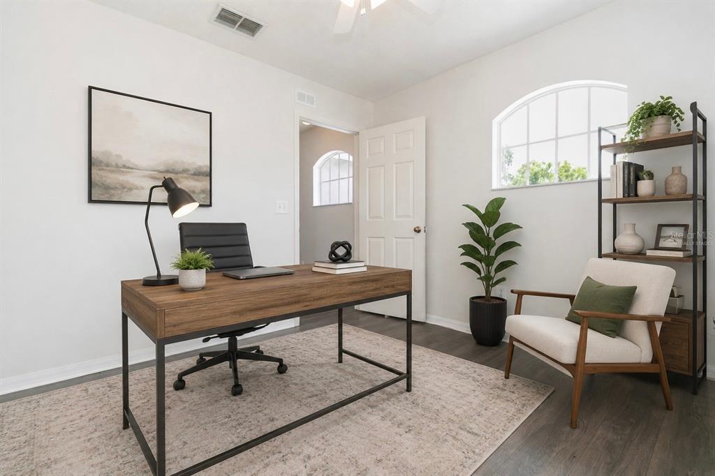 A home office featuring a wooden desk, an armchair, a bookshelf, and a large window — 28632 SEASHELL COURT, WESLEY CHAPEL, FL