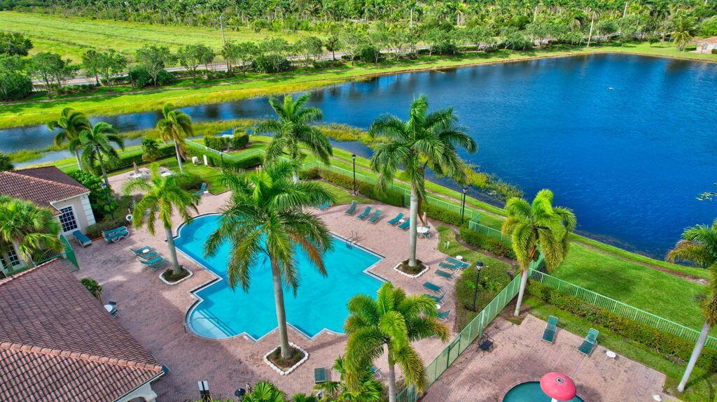 An aerial view of a community swimming pool and patio area next to a lake — 6689 Old Farm Trail, Boynton Beach FL 33437, BOYNTON BEACH, FL