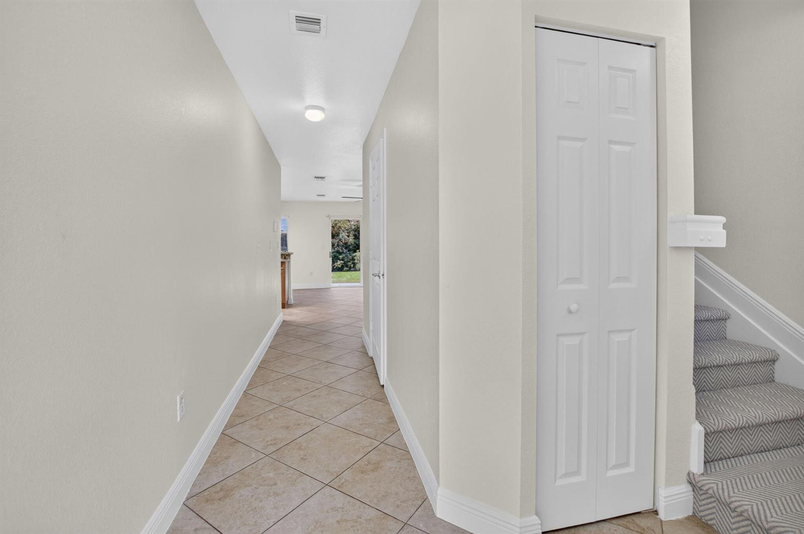 A hallway with tile flooring leads to a living area with stairs on the right — 6689 Old Farm Trail, Boynton Beach FL 33437, BOYNTON BEACH, FL