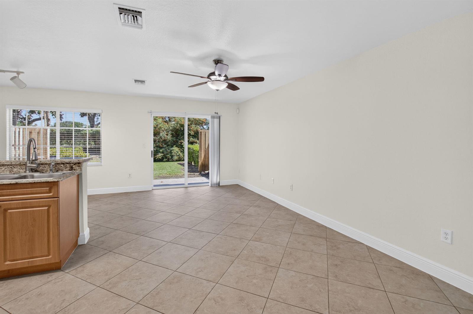 An open-concept dining area features tile flooring, a ceiling fan, and sliding glass patio doors — 6689 Old Farm Trail, Boynton Beach FL 33437, BOYNTON BEACH, FL