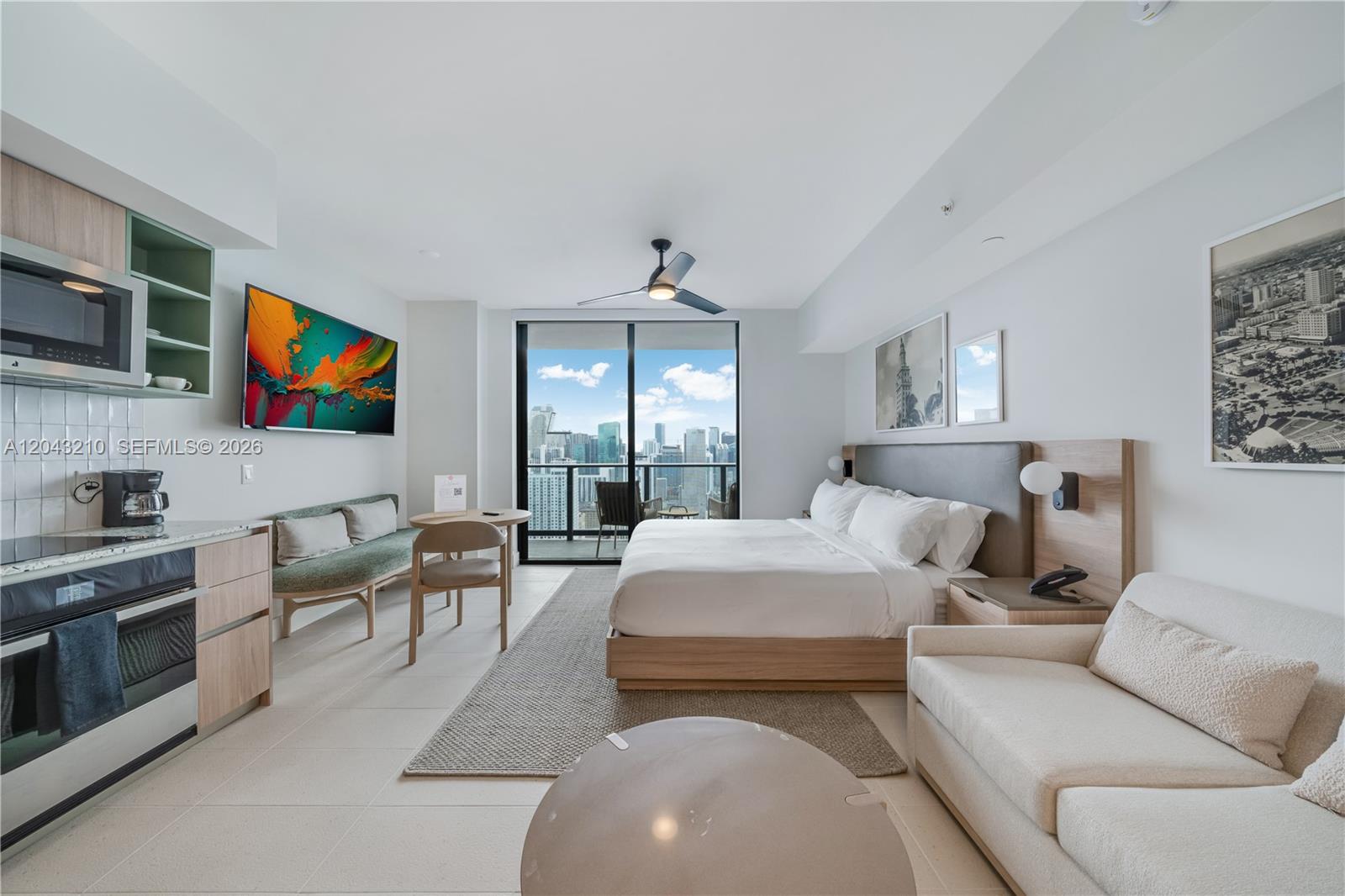 A modern studio apartment features a kitchenette, a bed, a sofa, and a balcony view — 159 NE 6th St # 4212, Miami FL 33132, MIAMI, FL