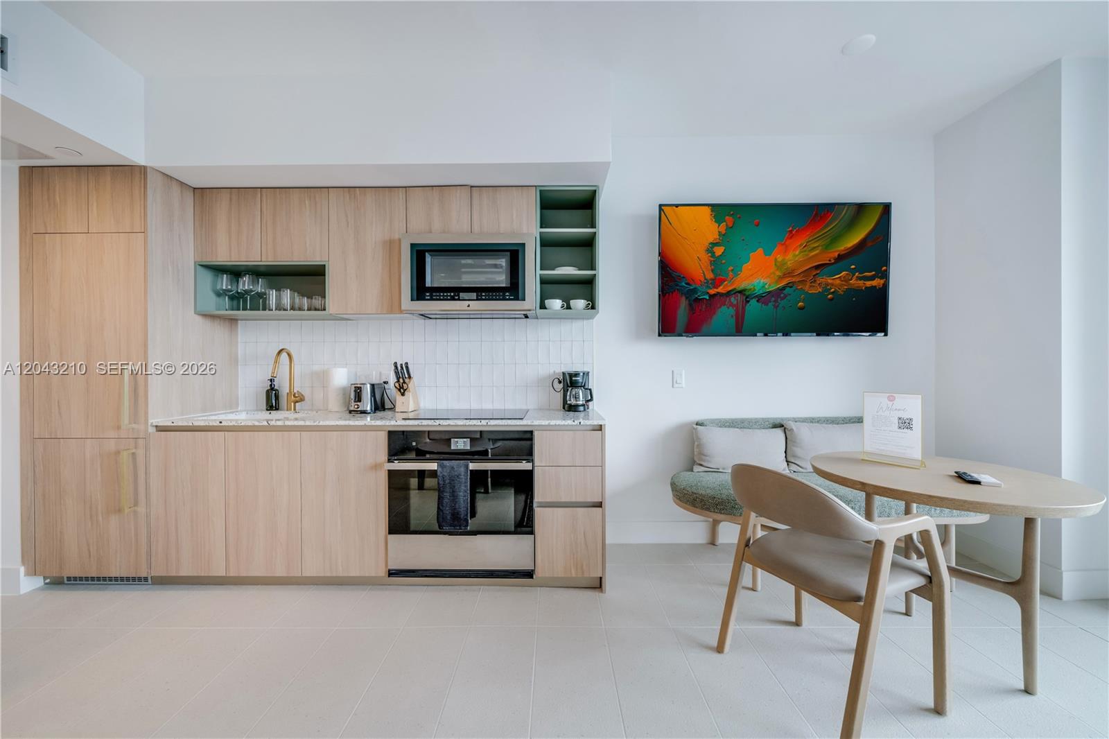 A modern kitchen features light wood cabinets, a built-in oven, and an adjacent dining area — 159 NE 6th St # 4212, Miami FL 33132, MIAMI, FL