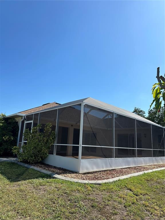 A screened-in patio enclosure is attached to the rear of a residential home — 8171 ROCLIFF AVENUE, NORTH PORT, FL