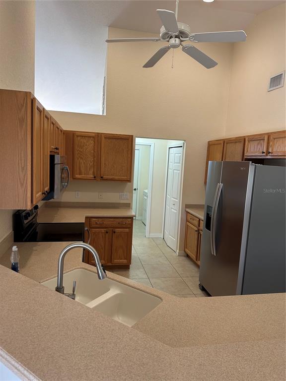 A kitchen features oak cabinets, laminate countertops, a stainless steel refrigerator, and a ceiling fan — 8171 ROCLIFF AVENUE, NORTH PORT, FL