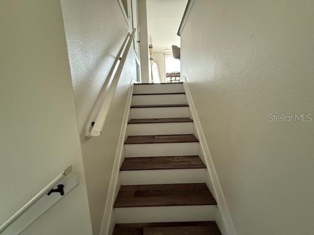 A staircase with dark wood treads and white risers leads to an upper floor landing — 8546 GREAT EGRET TRACE, NEW PORT RICHEY, FL