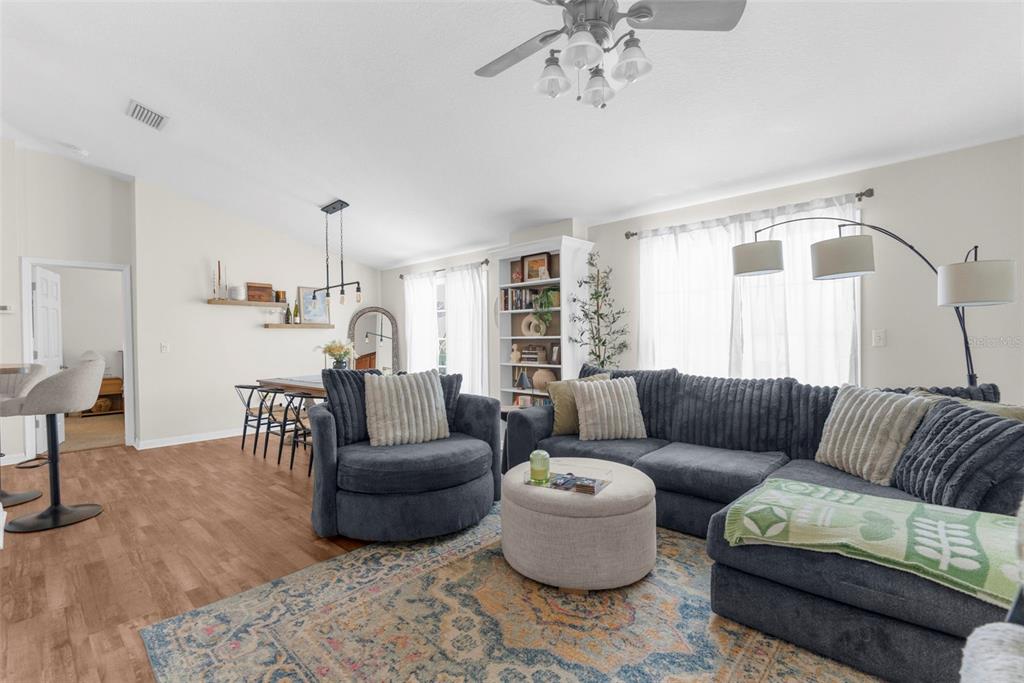 A living room features a dark sectional sofa, a round ottoman, and a dining area — 8546 GREAT EGRET TRACE, NEW PORT RICHEY, FL