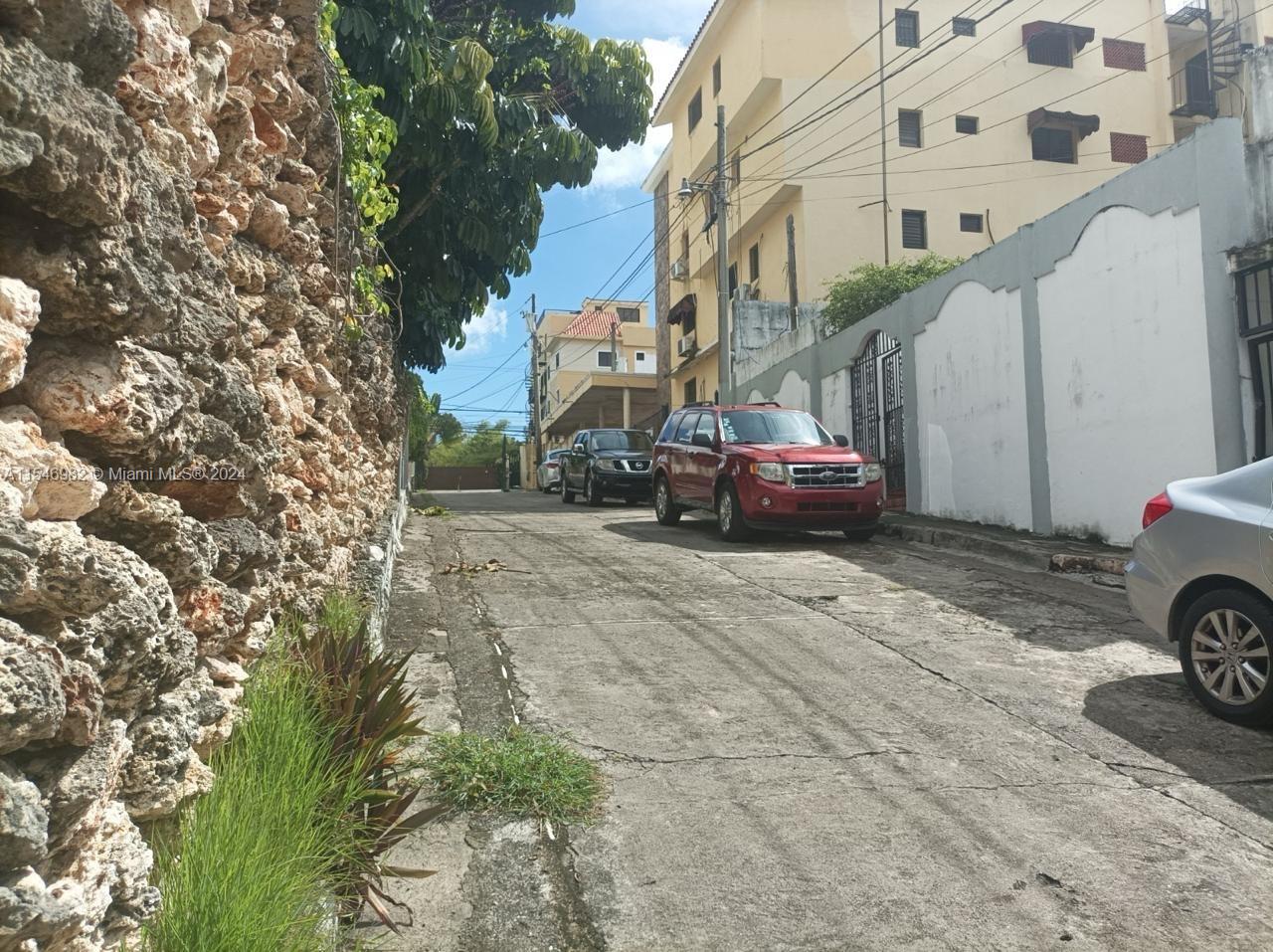 A narrow street features a stone wall on the left and parked cars on the right — 66-B ARROYO HONDO VIEJO DN, 0 0, 0