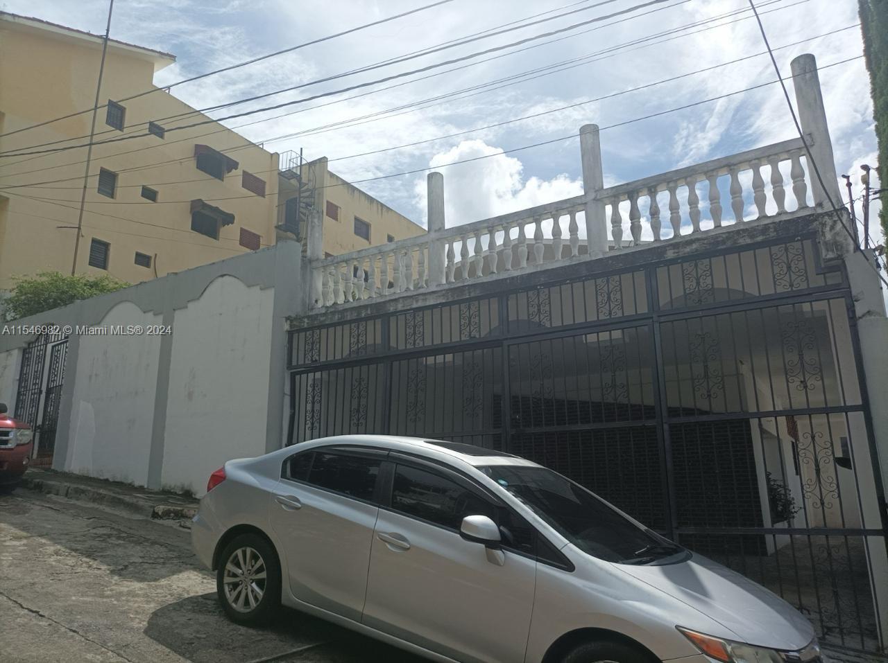A silver sedan is parked in front of a building with a gated entrance and balcony — 66-B ARROYO HONDO VIEJO DN, 0 0, 0