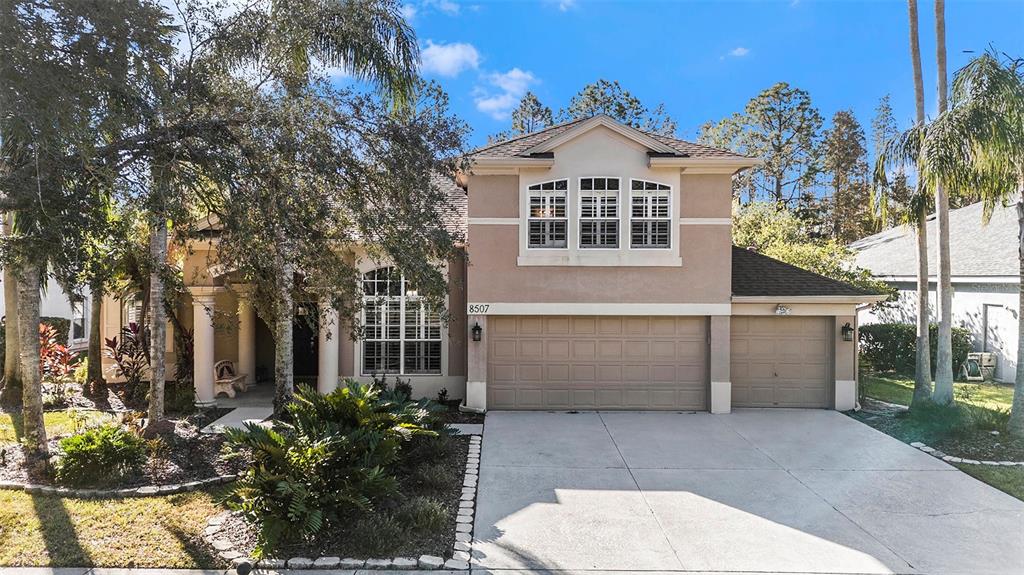 A two-story house with a beige stucco exterior, a three-car garage, and palm trees — 8507 PORTAGE AVENUE, TAMPA, FL
