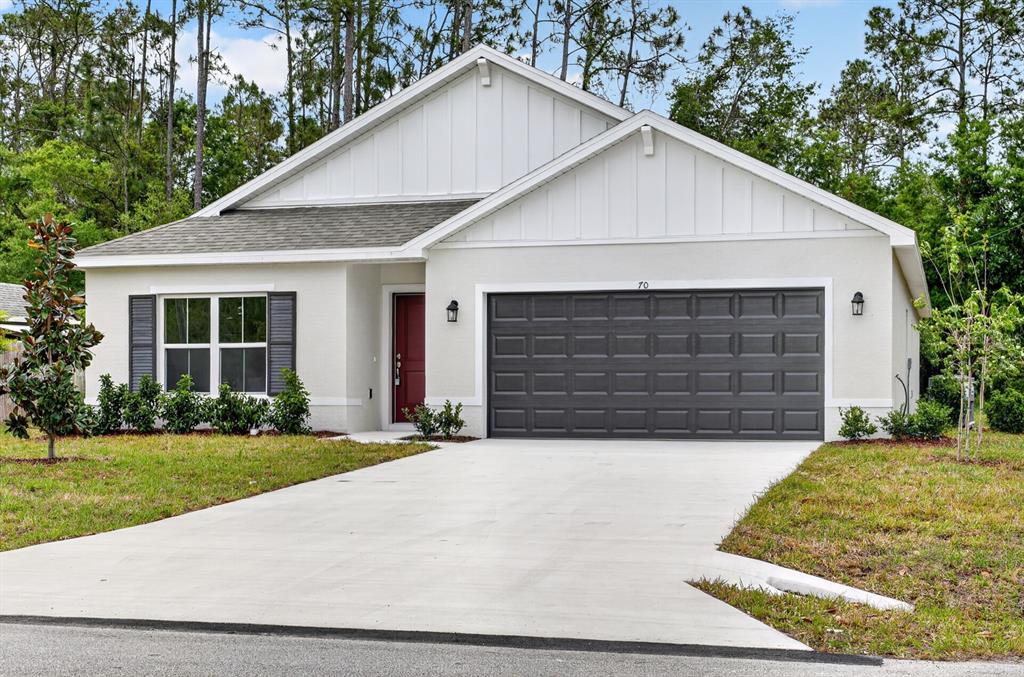 A single-story house with a white exterior, dark gray garage door, and a red front door — 70 WELLWATER DRIVE, PALM COAST, FL