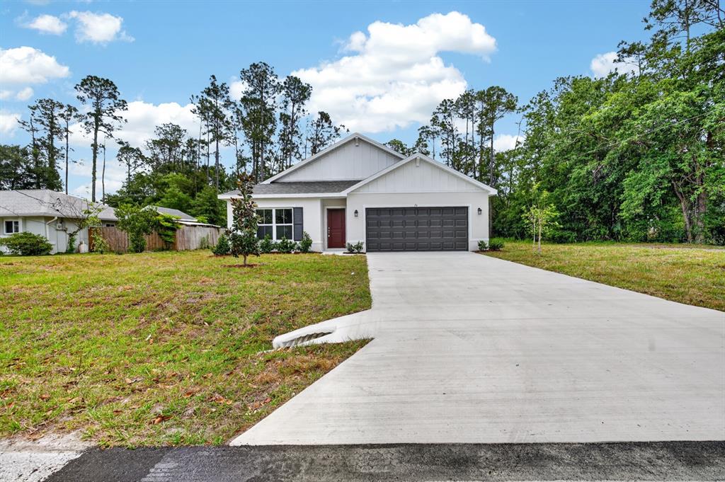 A single-story white house with a dark garage door and a red front door — 70 WELLWATER DRIVE, PALM COAST, FL