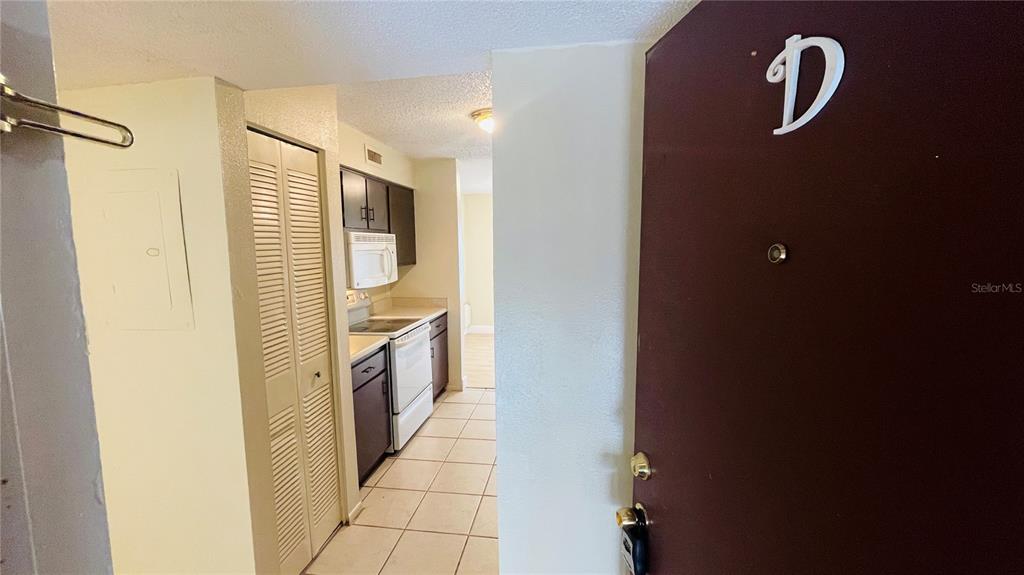 A view from an entryway looking into a kitchen with tile floors and white appliances — 7504 NEEDLE LEAF PLACE UNIT 68, TAMPA, FL