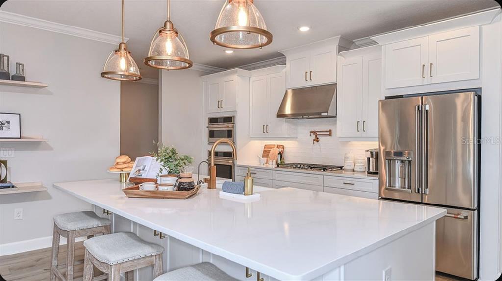 A modern kitchen features white cabinetry, stainless steel appliances, a large island, and pendant lighting — 109 ARMOYAN DRIVE, PALM COAST, FL