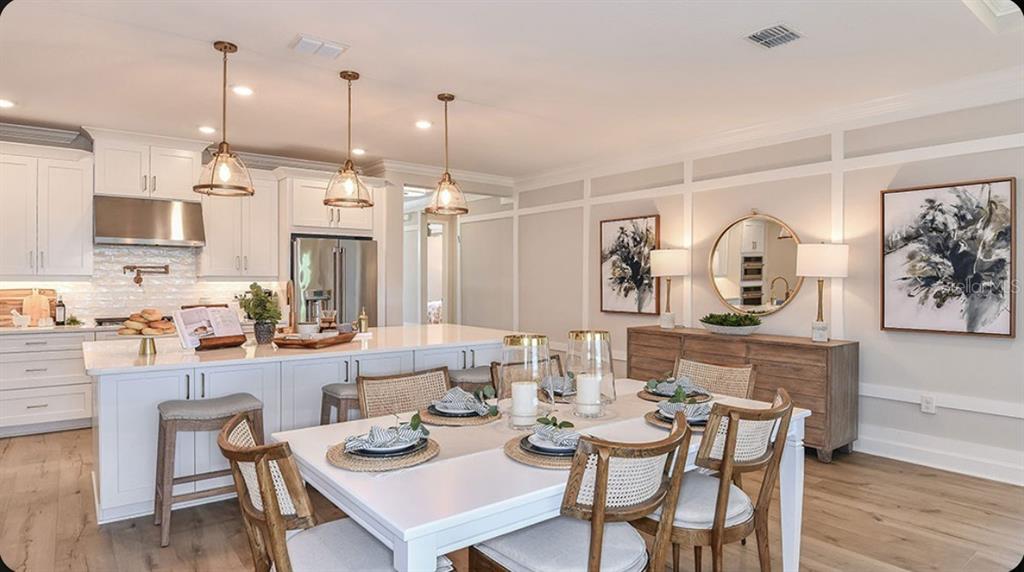 A bright kitchen and dining area with white cabinetry, a large island, and wood flooring — 109 ARMOYAN DRIVE, PALM COAST, FL