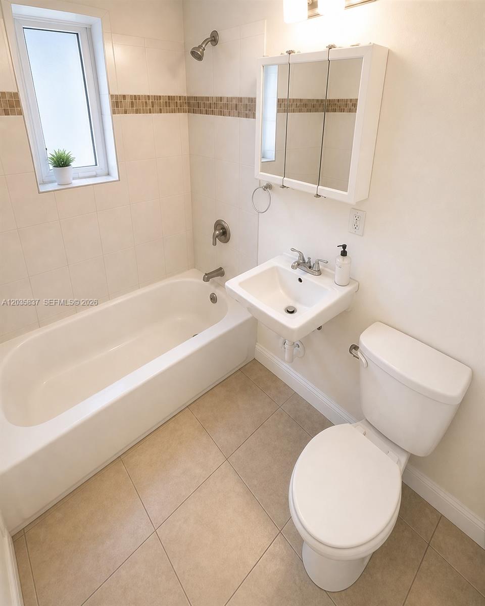 A bathroom features a white bathtub, a wall-mounted sink, a toilet, and tiled flooring — 1533 NW 2nd Ave # 6, Miami FL 33136, MIAMI, FL