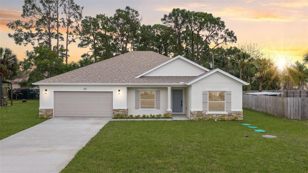 A single-story house with a beige stucco exterior, stone accents, and a two-car garage — 357 GALICIA STREET SW, PALM BAY, FL