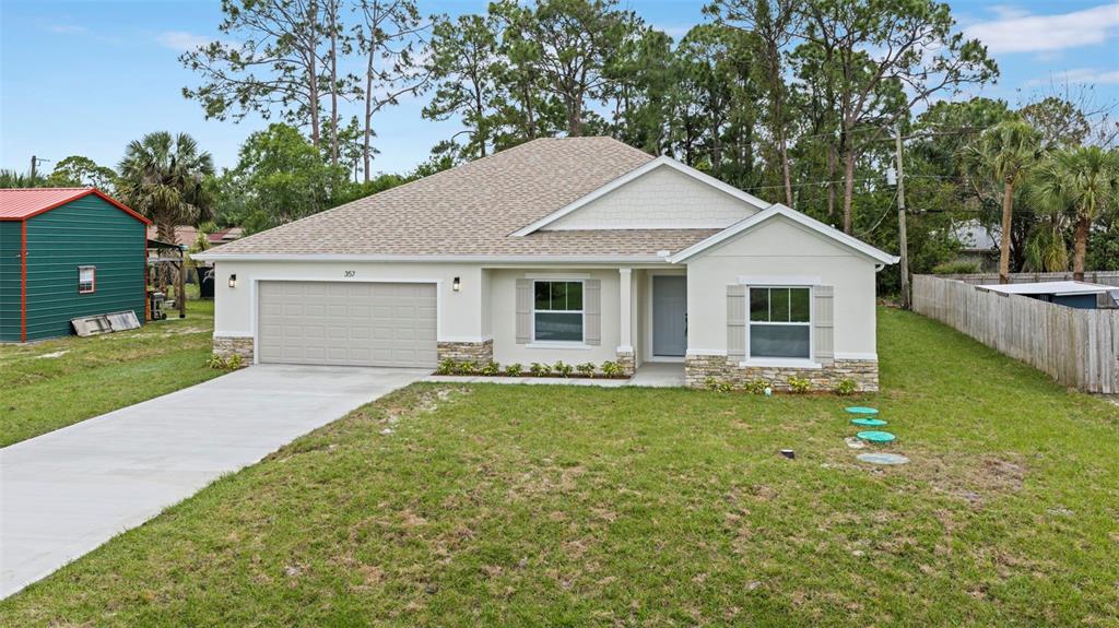 A single-story house with a beige exterior, stone accents, and a two-car garage — 357 GALICIA STREET SW, PALM BAY, FL