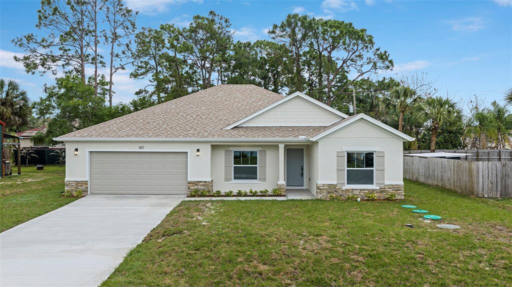 A single-story house with a beige stucco exterior, stone accents, and a two-car garage — 357 GALICIA STREET SW, PALM BAY, FL