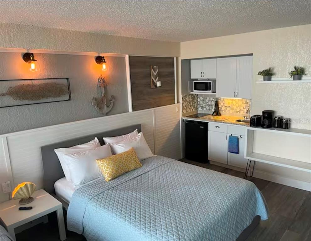 A studio apartment featuring a bed, kitchenette, and nautical-themed wall decor — 2301 S ATLANTIC AVENUE UNIT 337, DAYTONA BEACH, FL