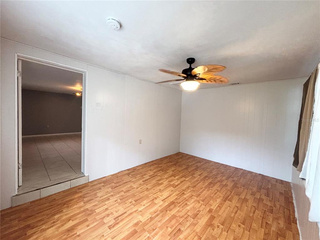 A room with wood-look flooring, white paneled walls, and a ceiling fan with leaf-shaped blades — 26 S OSCEOLA STREET, BEVERLY HILLS, FL
