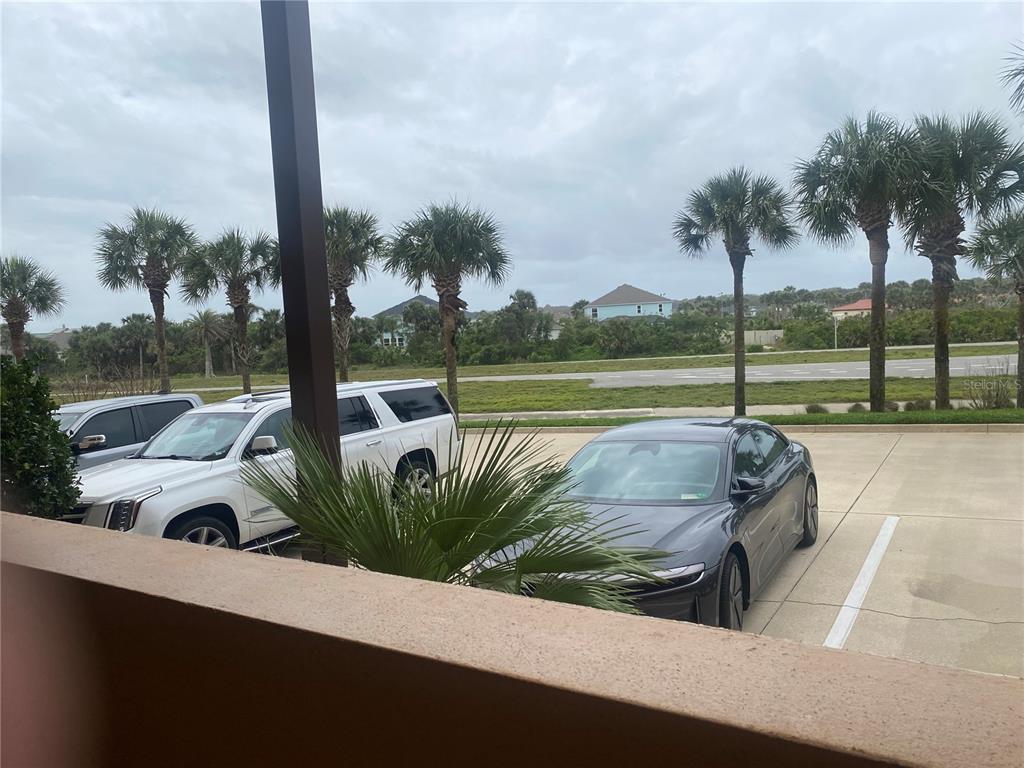 A view from a balcony overlooking a parking lot with cars and palm trees — 60 SURFVIEW DRIVE UNIT 121, PALM COAST, FL