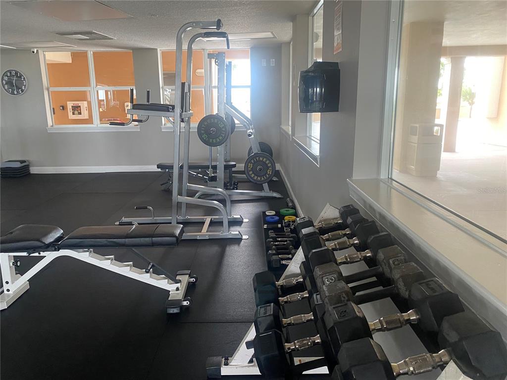 A gym features a weight bench, a pull-up station, and a rack of dumbbells — 60 SURFVIEW DRIVE UNIT 121, PALM COAST, FL