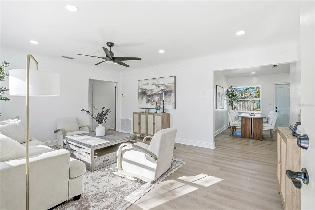 A bright living room with white walls, light wood floors, and a dining area beyond — 4720 MOHEGAN ROAD, ST PETERSBURG, FL